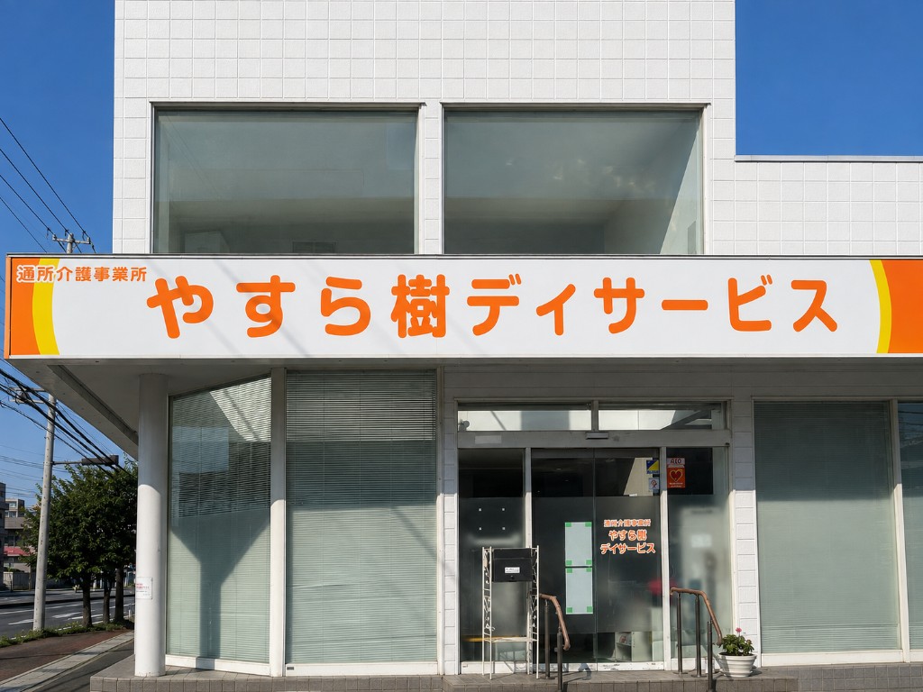 通所介護事業所やすら樹の外観。白い建物にオレンジの看板がある